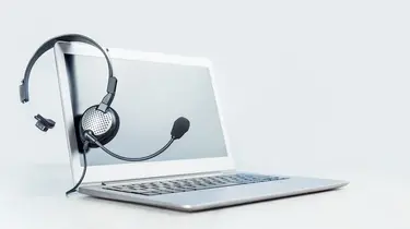 Silberner Laptop mit Headset über dem Bildschirm