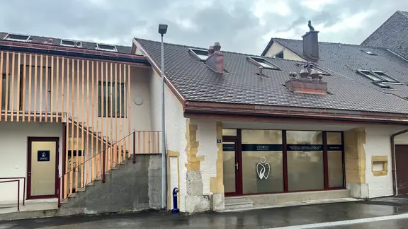 Links mit moderner Holzverkleidung und auf der rechten Seite weiss verputztes Haus mit Sandsteinbossen in Cornaux