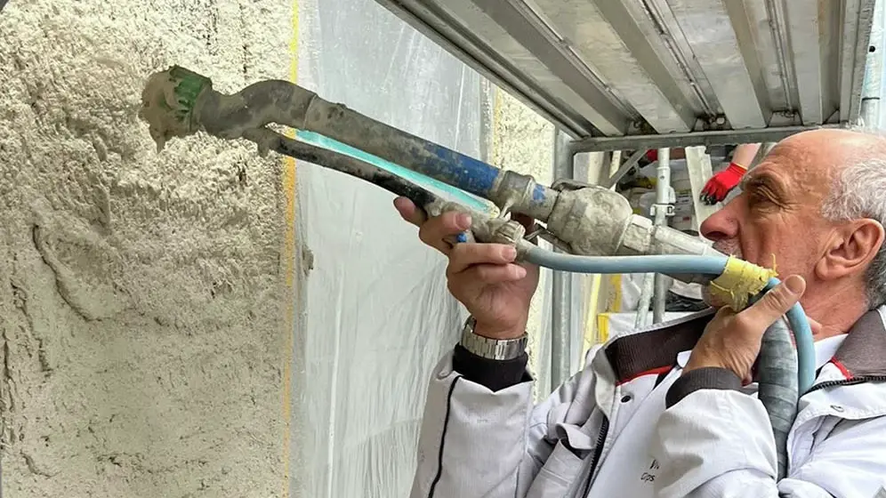 Vito Serratore applique l'enduit isolant CalceClima® sur un mur à l'aide d'une buse.
