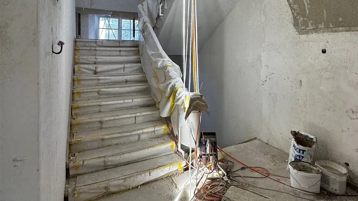 Historisches Treppenhaus im Rohzustand mit gewölbter Decke, Baustrahler und Fixit 163 Produkt Sack 