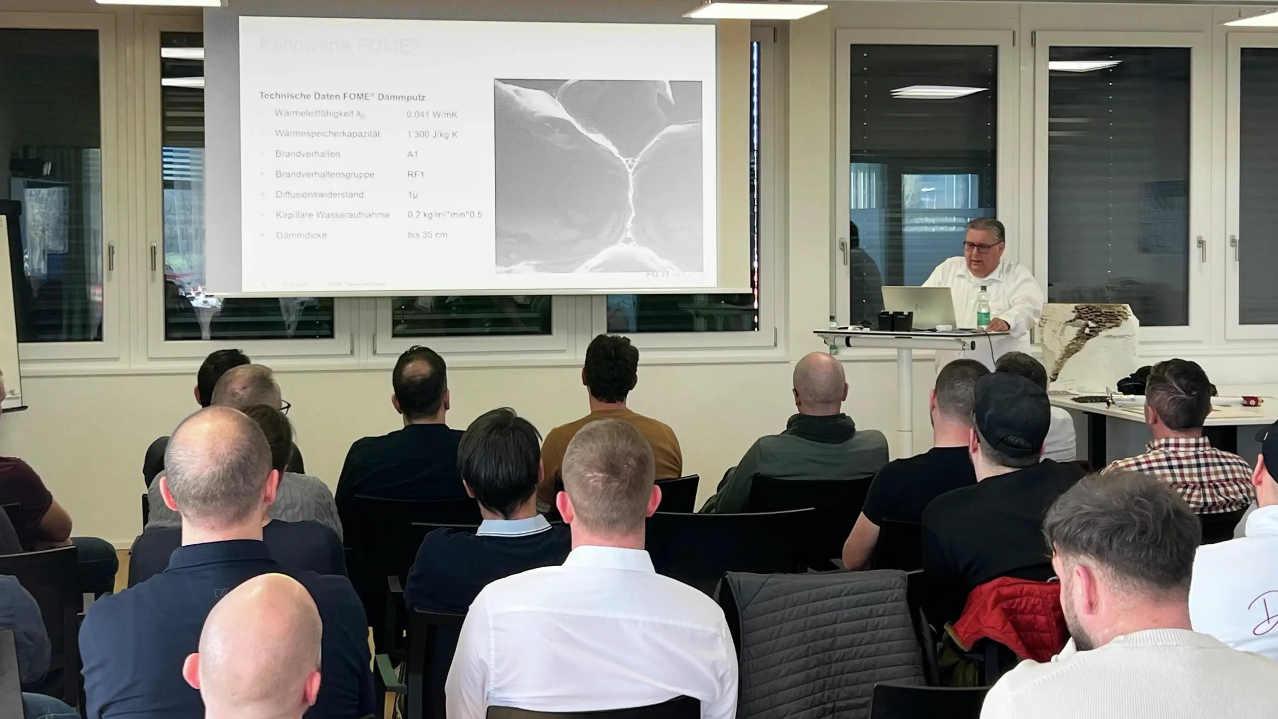 Werner Wälle präsentiert die Folie mit den FOME® Dämmputz Vorteilen den aufmerksamen Gästen 