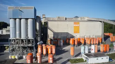 Gesamtansicht Produktionshalle Fixit AG Holderbank mit LKW-Silos und stehenden Fixit Silos in orange