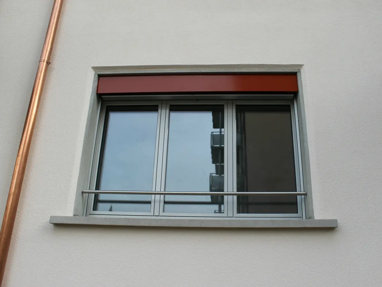 Detailansicht eines Fensters in der fertigen Aussenfassade mit Kupferrohr