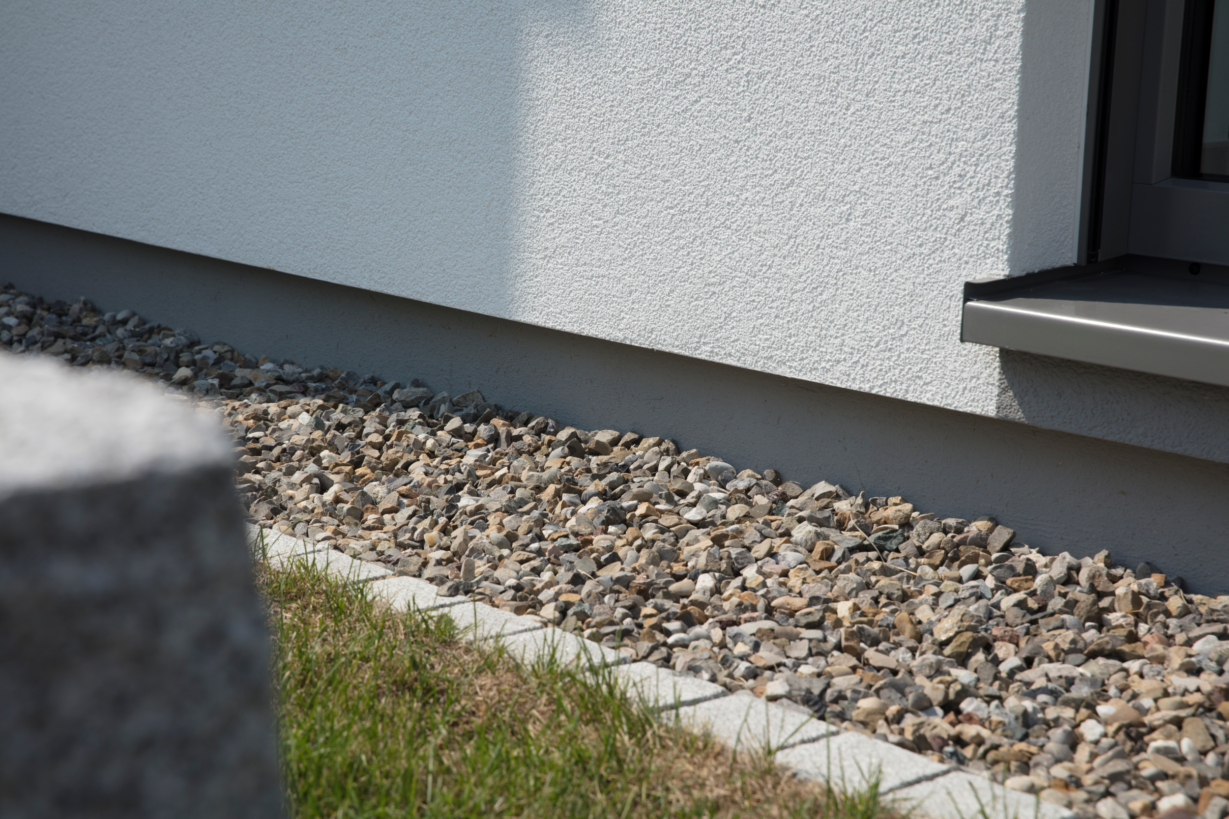 Der Sockelbereich einer Außenfassade, sorgfältig verputzt und verstärkt, bietet Schutz vor Feuchtigkeit und Beschädigungen. 