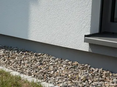 Der Sockelbereich einer Außenfassade, sorgfältig verputzt und verstärkt, bietet Schutz vor Feuchtigkeit und Beschädigungen. 