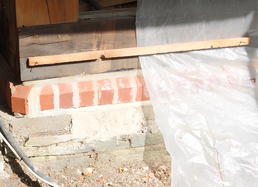 Auf dem Natursteinsockel sitzt jetzt eine Lage  vorne abgeschrägter Vollziegel, gefolgt von  einer Bitumen-Horizontalsperre 