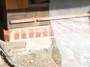 Auf dem Natursteinsockel sitzt jetzt eine Lage  vorne abgeschrägter Vollziegel, gefolgt von  einer Bitumen-Horizontalsperre 