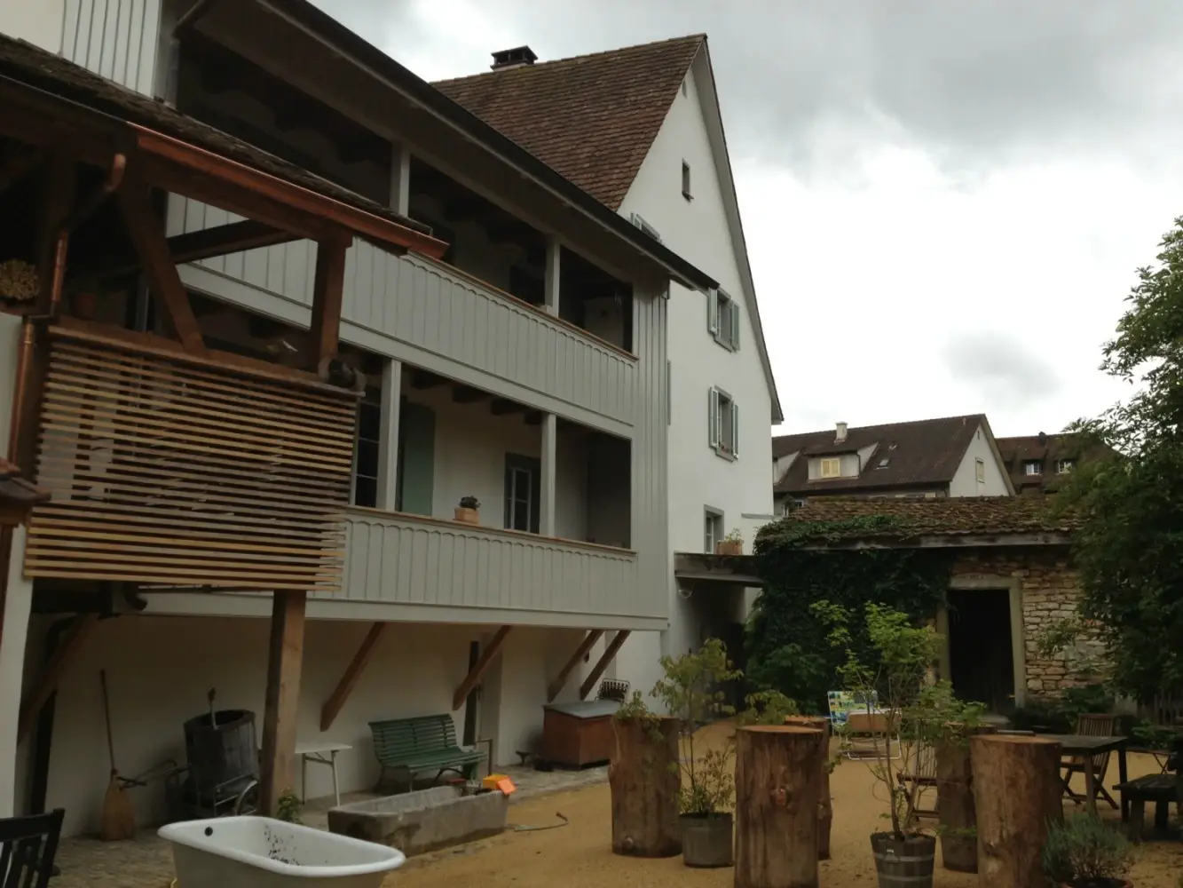 Aussenansicht der Rückseite mit Balkonbrüstungen aus Holz und Stehtischen 