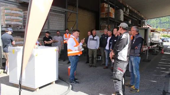 Links steht der Musterwürfel mit Fixit POR Schaumbeton, Remo Schwendener erklärt den umstehenden Teilnehmenden die Vorteile des Fixit Produkts