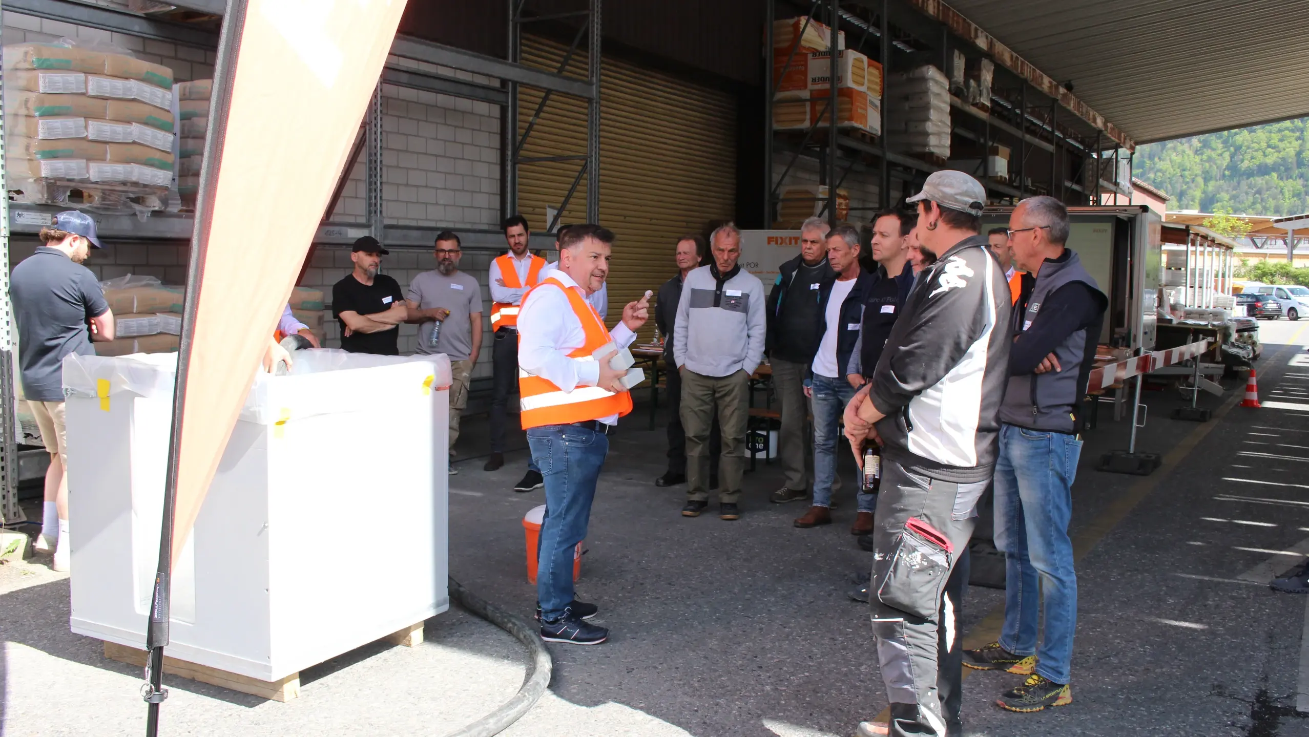 A gauche se trouve le cube d'échantillons avec Fixit POR béton mousse, Remo Schwendener explique les avantages du produit Fixit aux participants qui l'entourent.