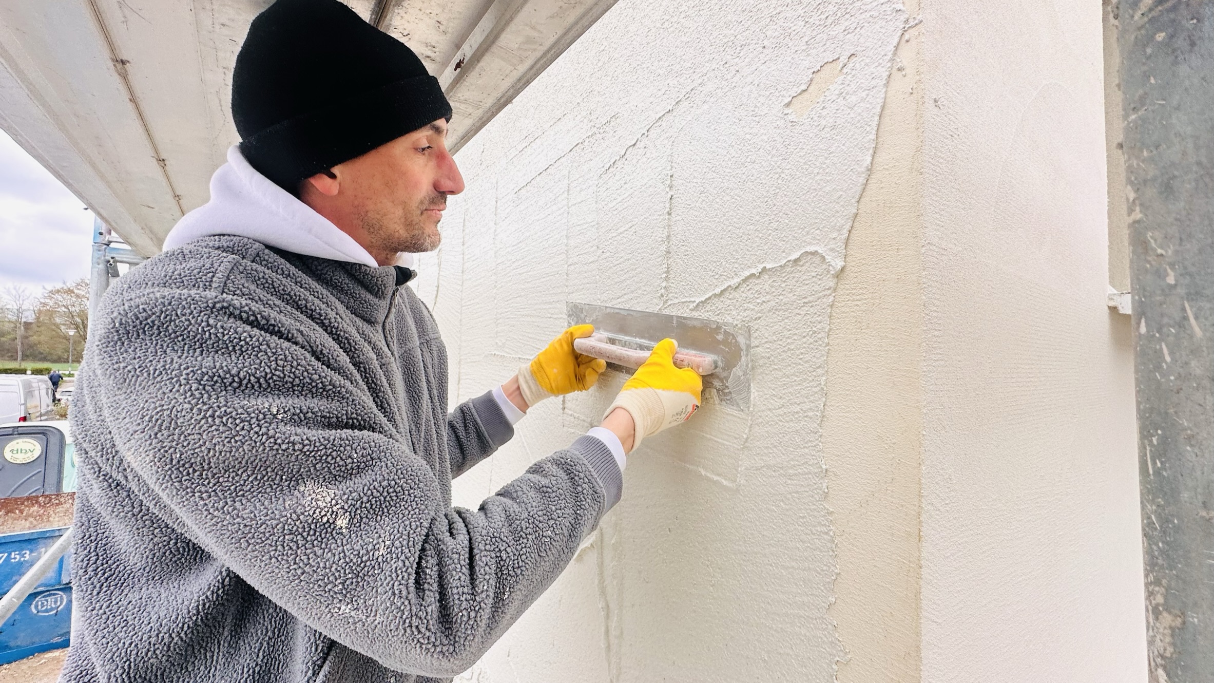 Der Putz wird mit einer Kelle an der Fassade verarbeitet