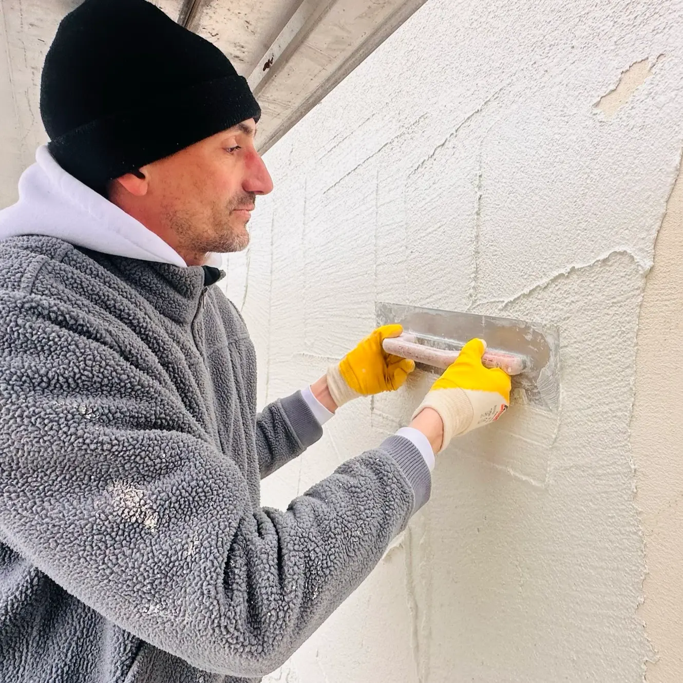 Der Putz wird mit einer Kelle an der Fassade verarbeitet