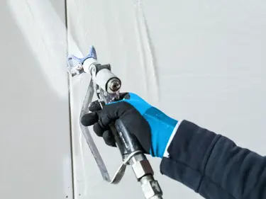 Spachtelmasse wird mithilfe einer Airless-Düse direkt und gleichmäßig auf die Wand gespritzt.