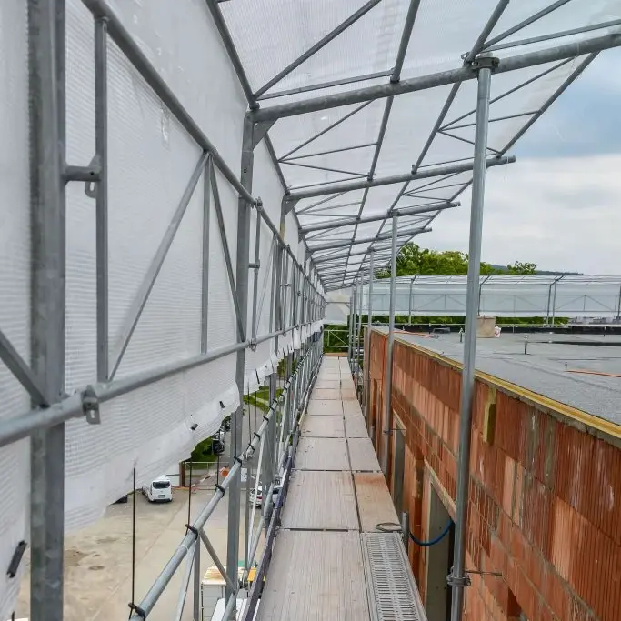 Baugerüst an der Flachdachkante mit einem Gerüstdach zum Schutz der Aussenfassade
