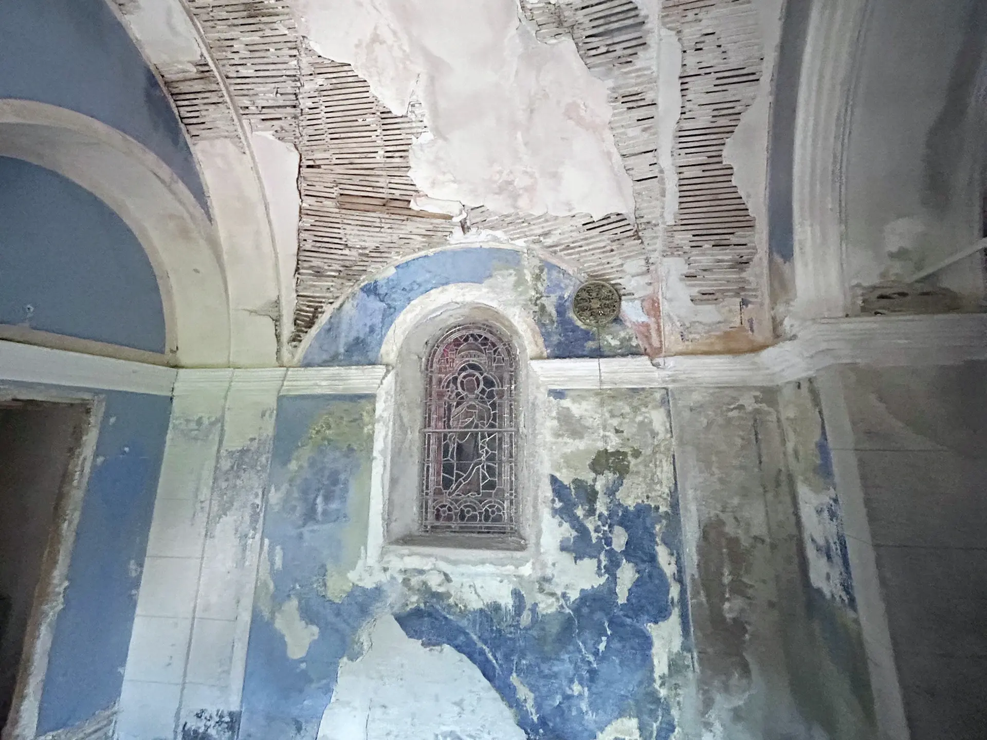 Intérieur : voûte nécessitant une rénovation, avec crépi écaillé et peinture bleue délavée.