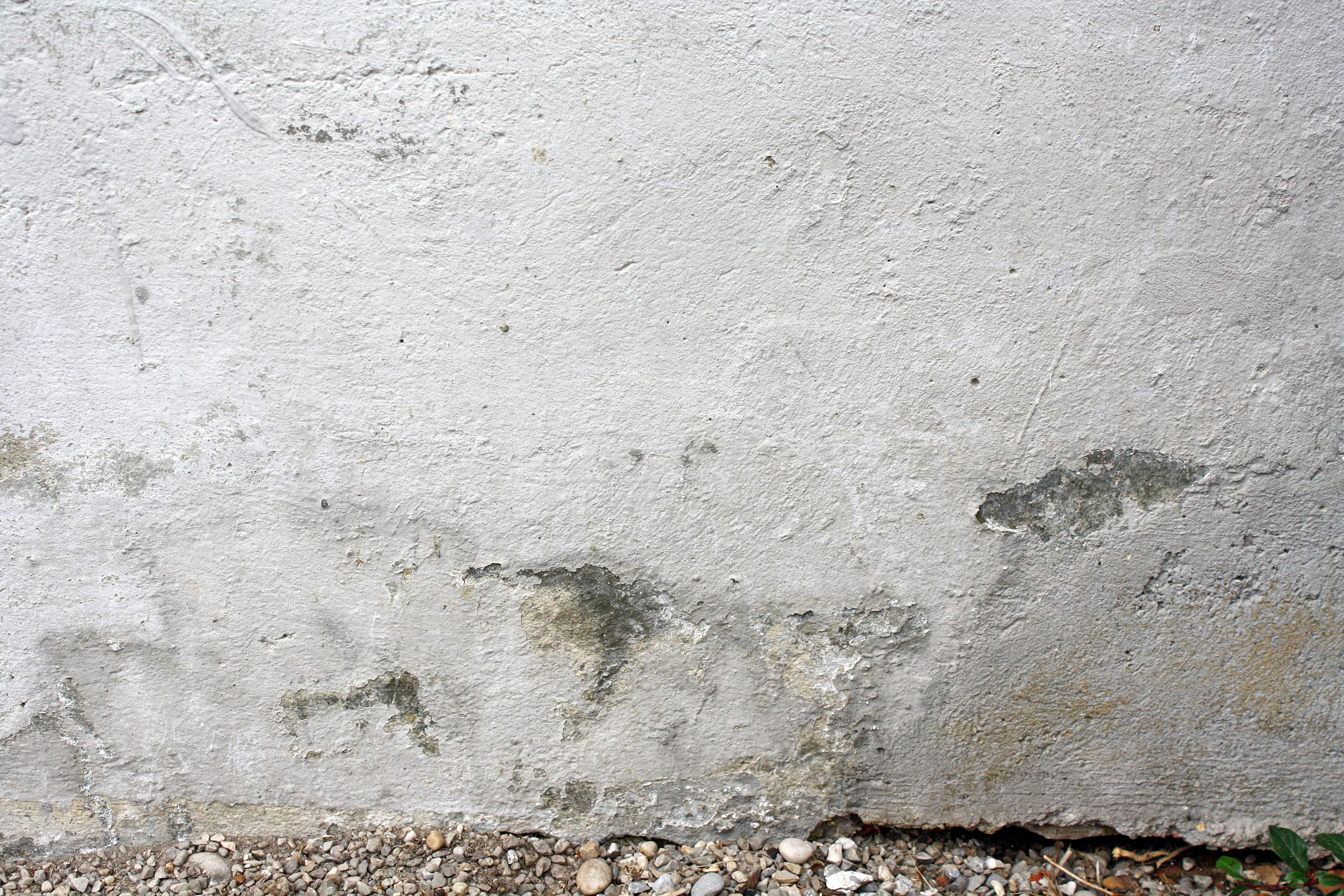 Detailansicht eines Gebäudesockels mit sichtbaren Putzschäden – hier ist eine Abdichtung notwendig. Unsere Reaktivabdichtung bietet die perfekte Lösung.