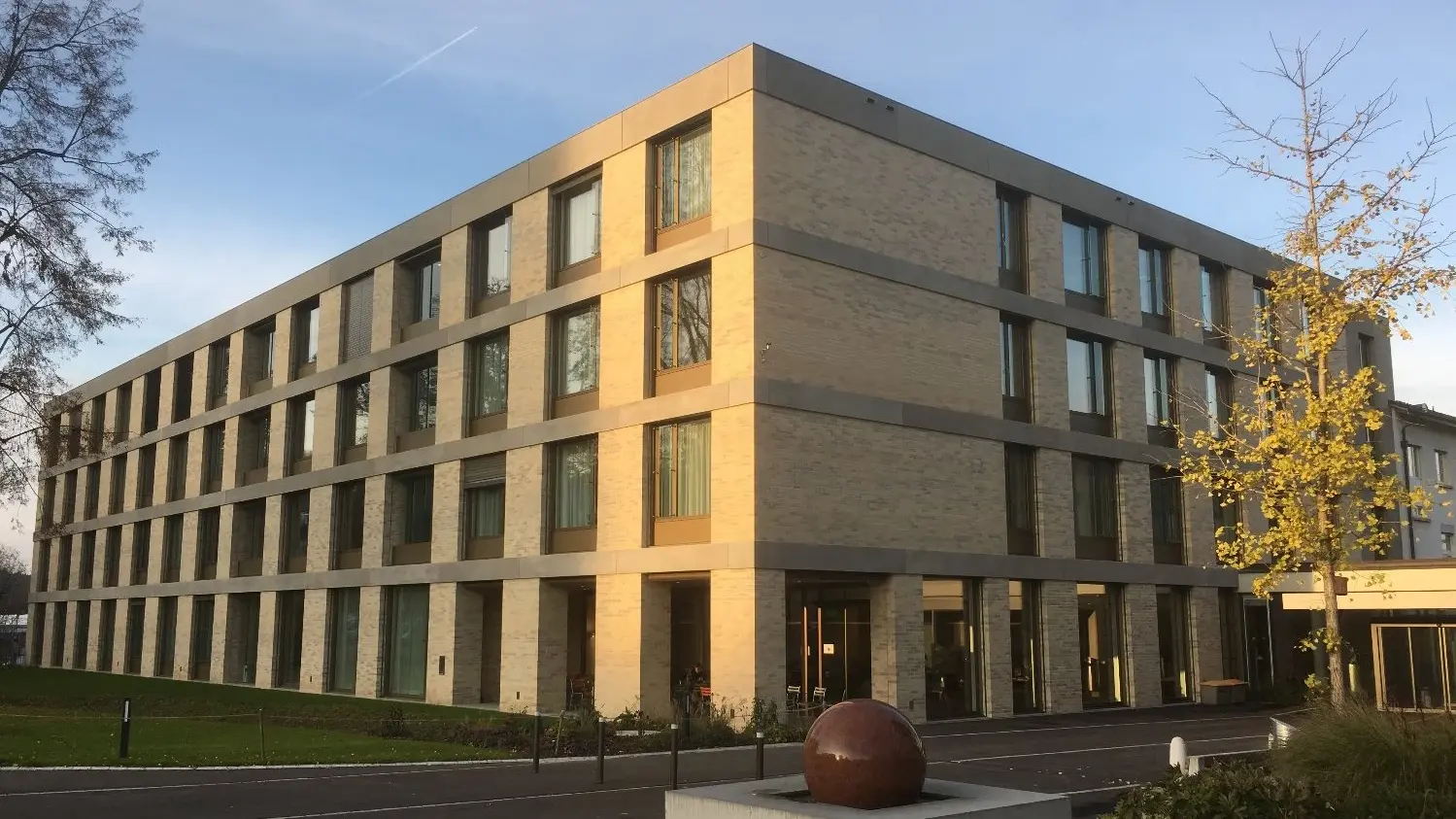 Aussenansicht der modernen Privatklinik mit der Fassade aus hellem Klinkerstein und abgesetzten Bändern