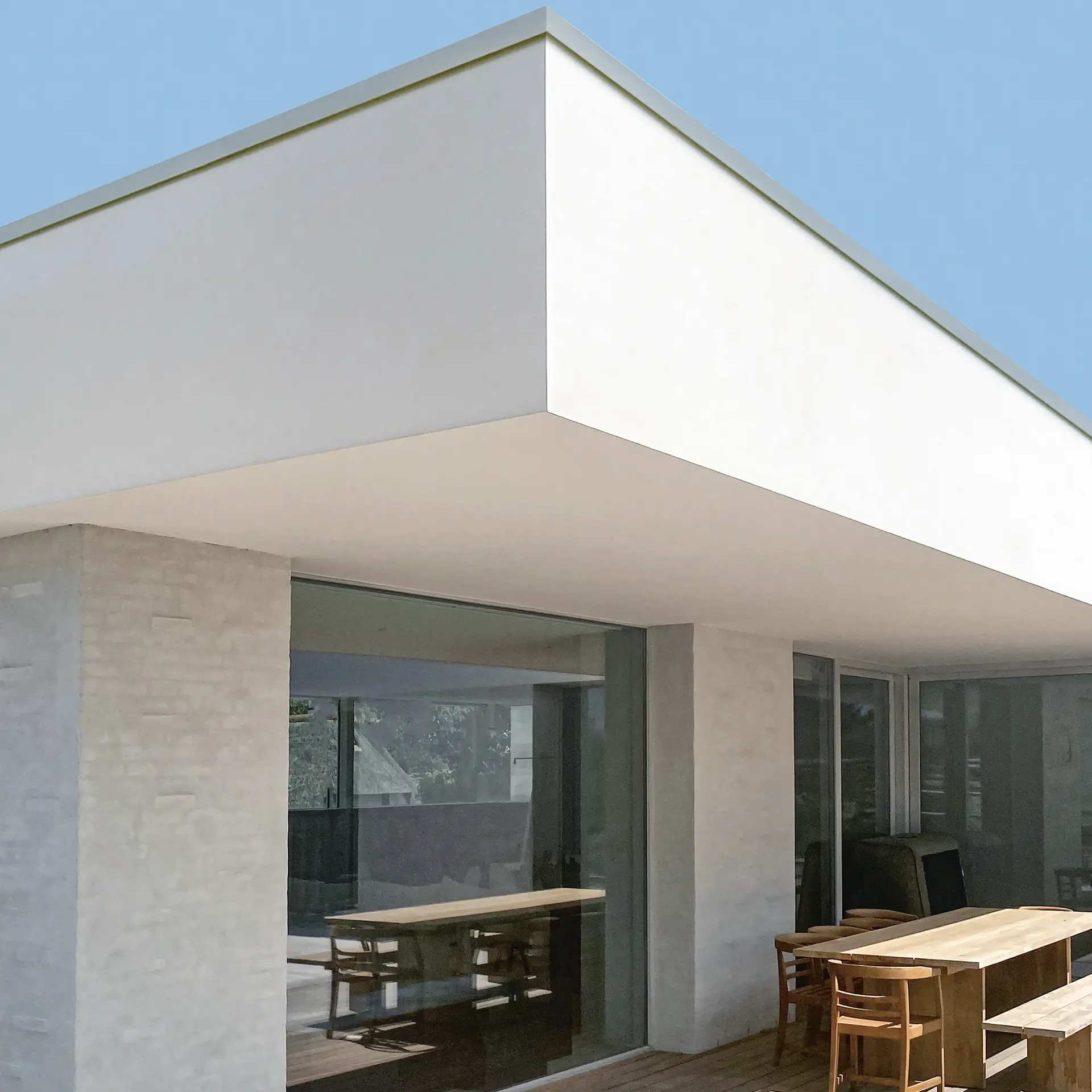 Vergleich Flachdach mit klassischer Attika-Dachkante und sichtbarem Dachrandabschluss, der die klare Fassadenlinie unterbricht