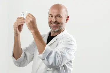 Ein Laborant hält Proben in der Hand.