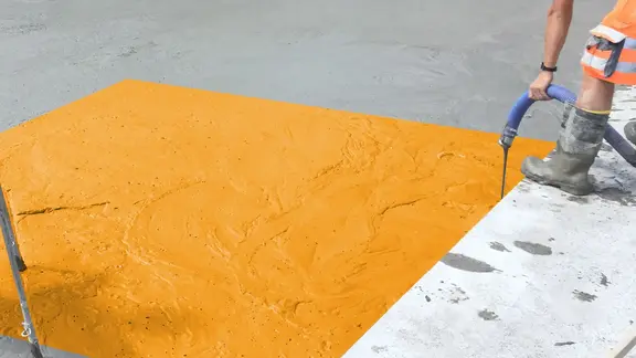 Fixit POR Schaumbeton wird vergossen, ein Teil der Fläche ist orange eingefärbt