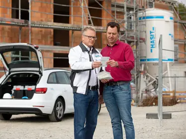 Der Verkaufsberater berät seinen Kunden auf der Baustelle.