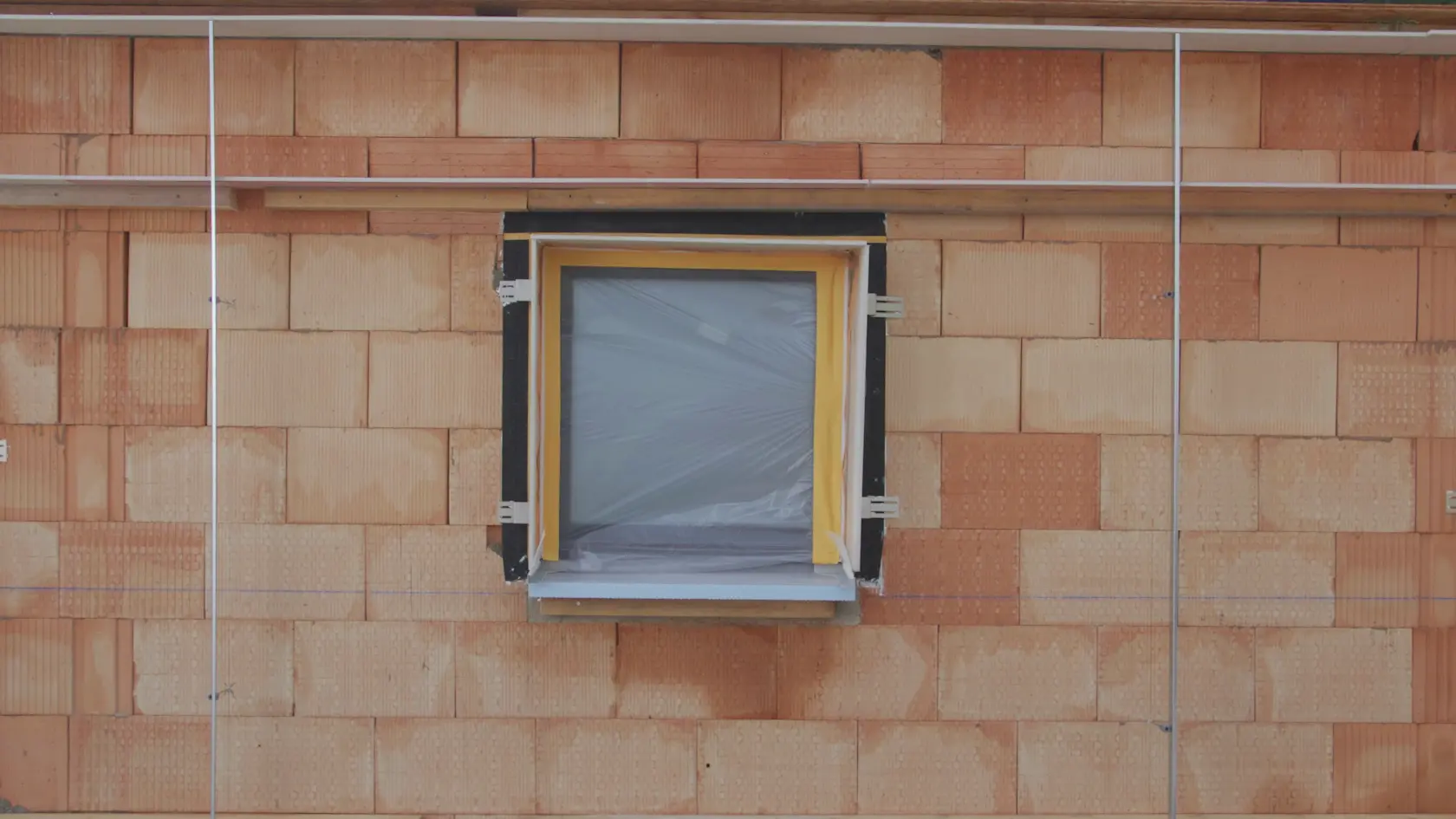 Frontansicht einer gemauerten Wand mit einem Fenster und Profilschienen
