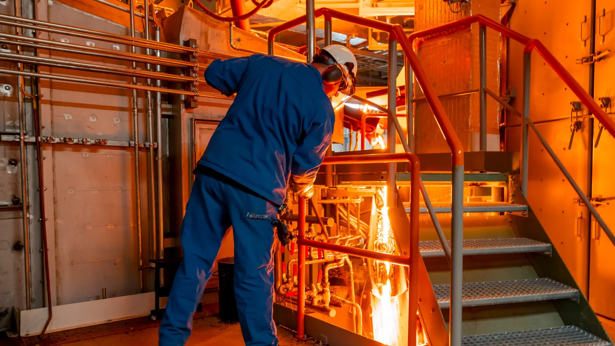 Un employé vêtu de bleu contrôle la fusion dans le four