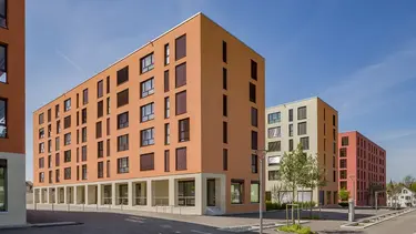 Drei Mehrfamilienhäuser in unterschiedlichen, gedeckten Erdtönen als Neubau im Projekt Düdingen-plus