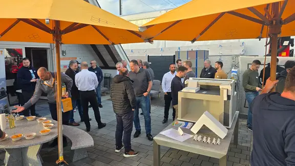 Aussenbereich mit Sonnenschirmen, Snacks und dem Muster zu Fixit RoofEtics® mit vielen Gästen im Gespräch