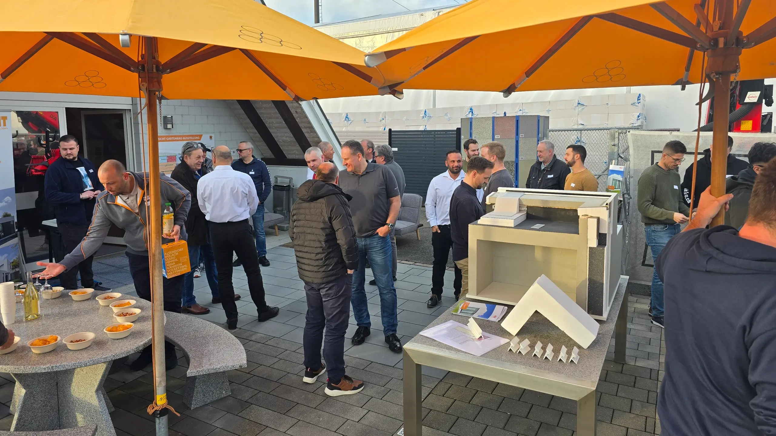 Aussenbereich mit Sonnenschirmen, Snacks und dem Muster zu Fixit RoofEtics® mit vielen Gästen im Gespräch