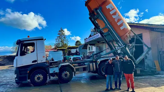 Drei Personen von BSC Constructions stehen vor dem Silo-LKW, während das Fixit Silo gerade aufgeladen wird