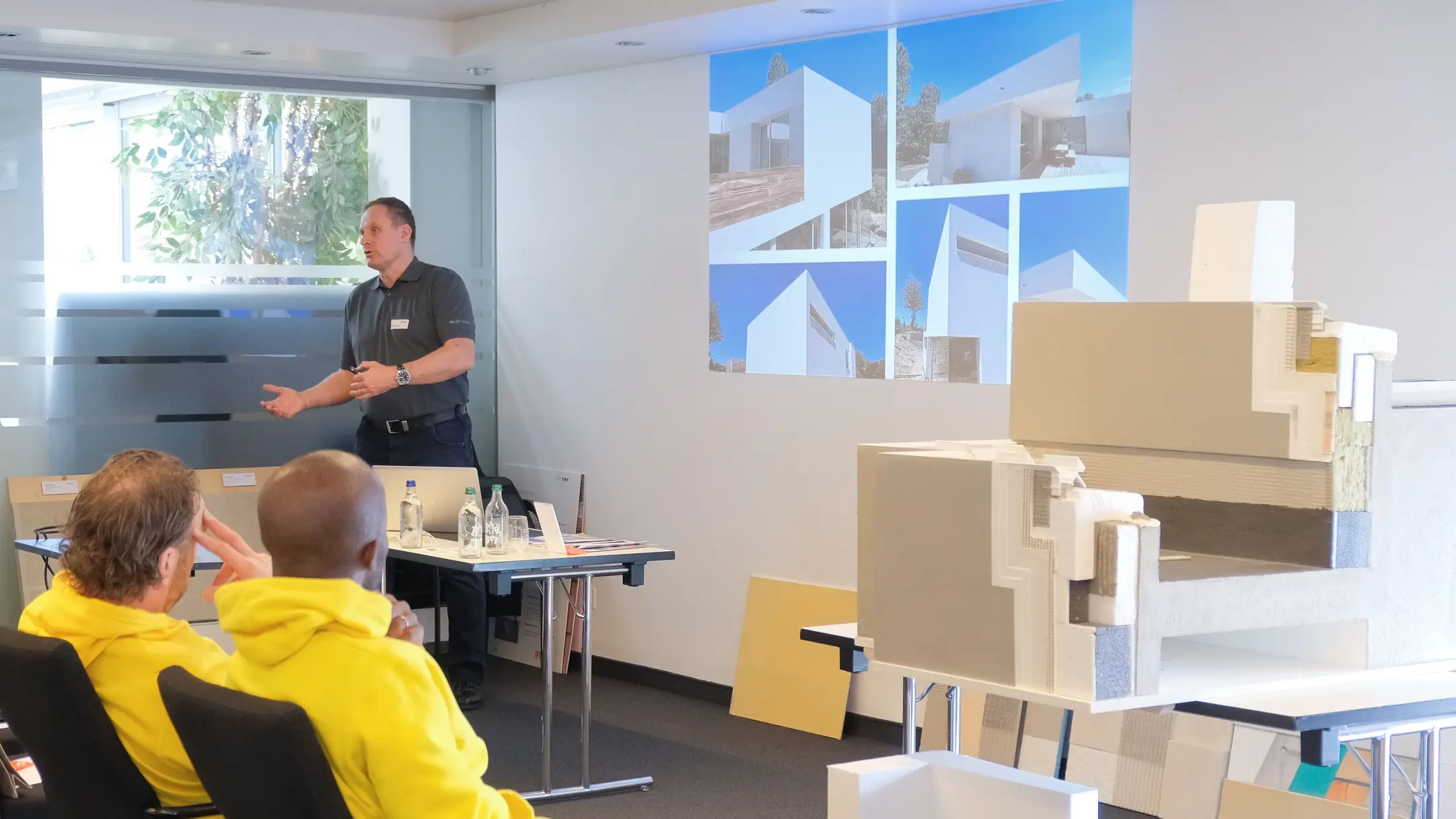 Ralf Bannwitz zeigt Bildbeispiele für Fixit RoofEtics® auf der Präsentation vor dem Publikum sowie das Ausführungsmuster rechts