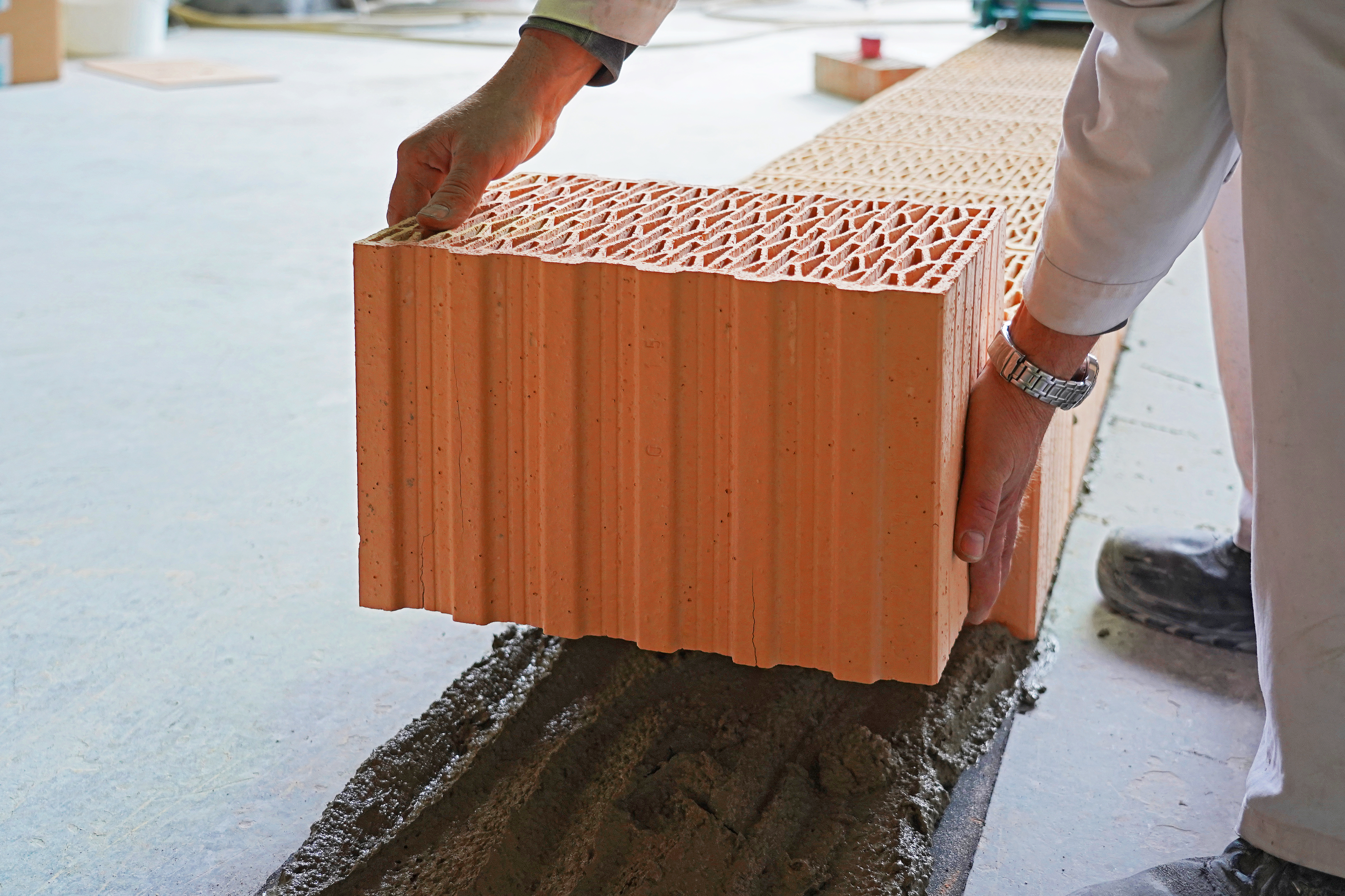 Ziegelsteine werden auf eine Schicht Mauermörtel platziert.