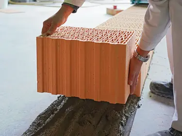 Ziegelsteine werden auf eine Schicht Mauermörtel platziert.