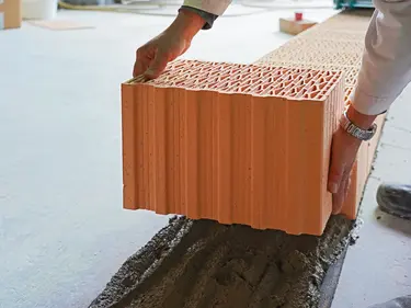 Ein Ziegel wird auf Mörtel draufgelegt 