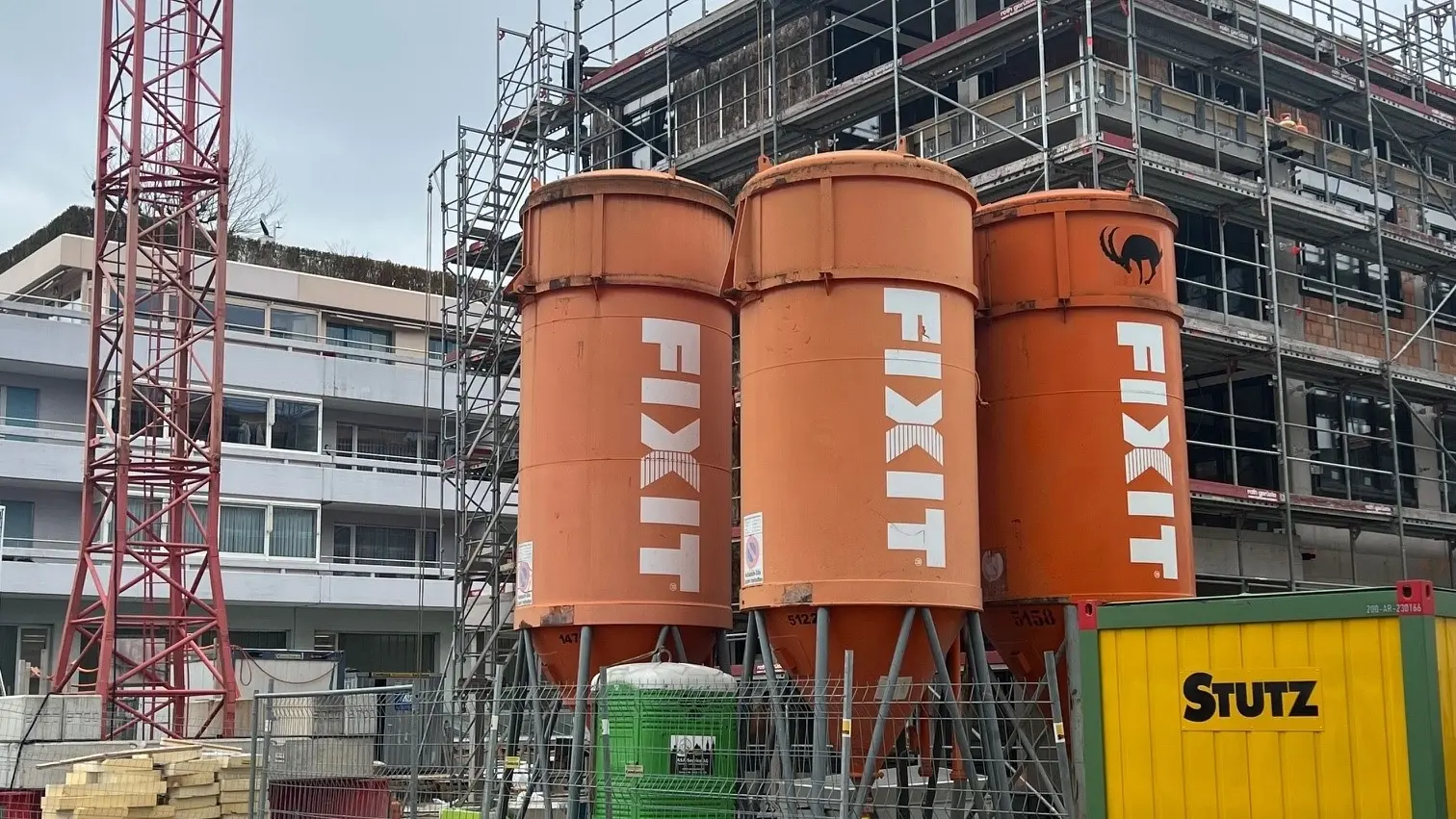 Drei Fixit Silos vor einem mehrstöckigen, eingerüsteten Gebäude