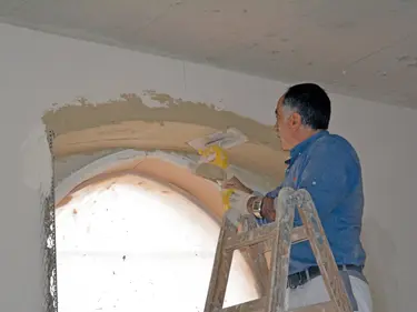 Ein Mann verputzt die Wand mit einer Kelle 