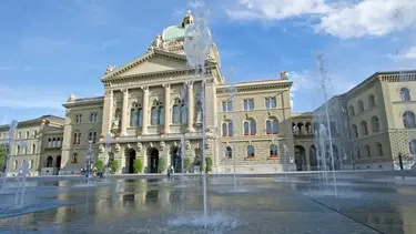 Das Bundeshaus Nord in Bern bei sonnigem Wetter und blauem Himmel mit dem Vorplatz und Wasserfontänen