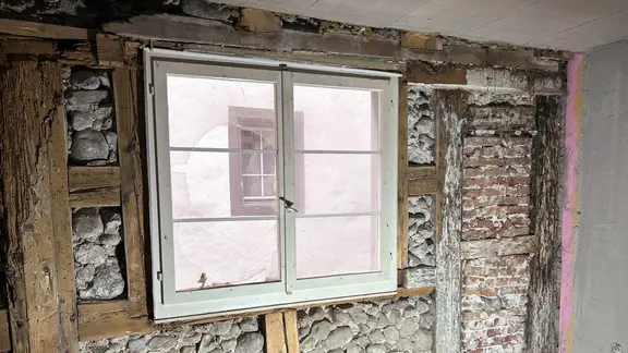 Mur extérieur historique avec protection du site, vue intérieure de la maçonnerie mise à jour et structure de poutres