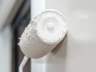 Mit einer Rolle wird die Wand weiß angestrichen