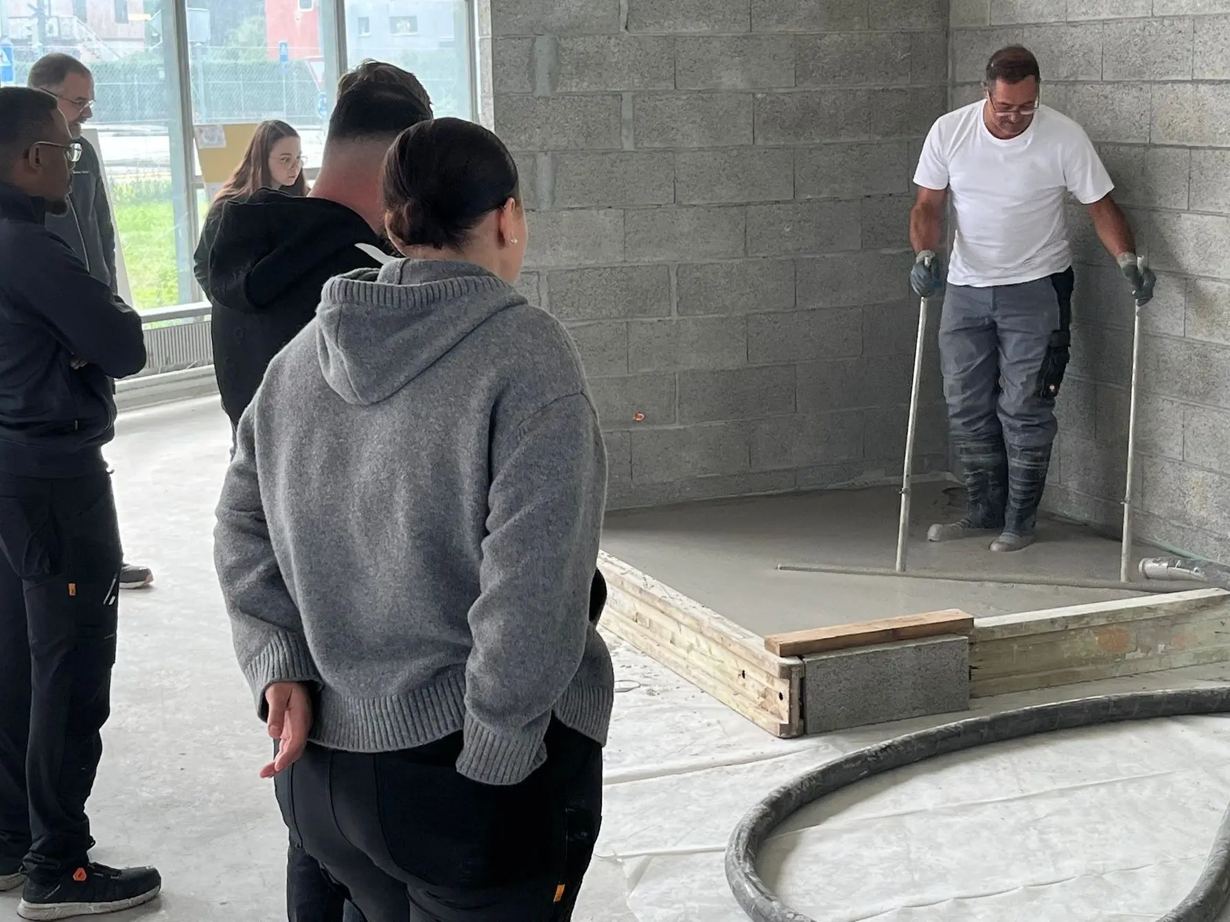 À gauche, six personnes assistent à la démonstration d'un technicien d'application Fixit sur le coulage du CAF et le polissage à l'aide d'une barre de polissage.