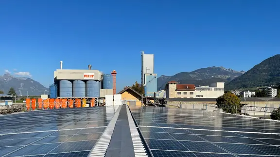 Installation photovoltaïque sur le bâtiment de l'usine de Fixit AG avec silos et hall de production en arrière-plan.