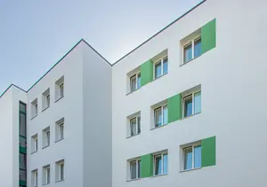 Modernes, gedämmtes Wohngebäude mit weißer Fassade und grünen Akzenten.