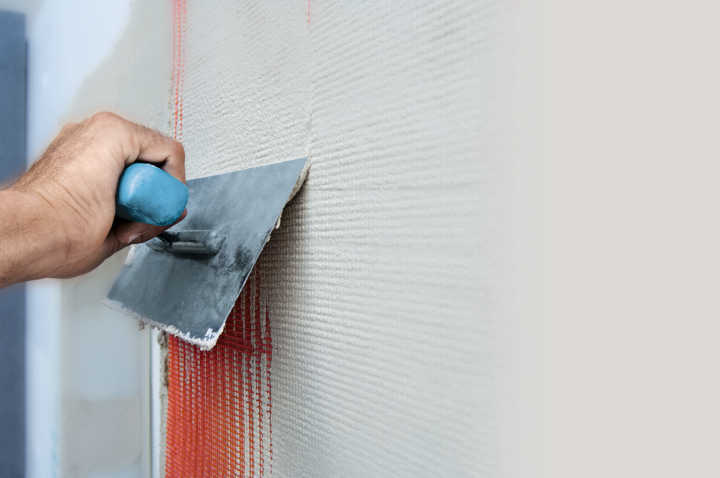 Eine Schicht Putz wird auf ein Armierungsgewebe aufgebracht.