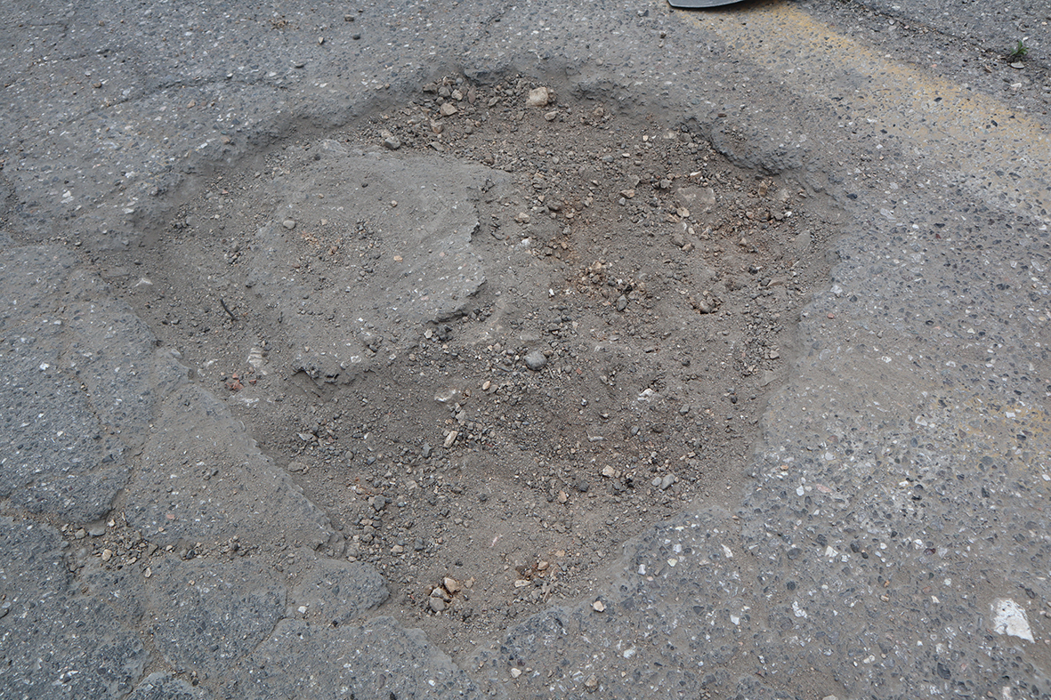 Beschädigte Straße mit einem Schlagloch