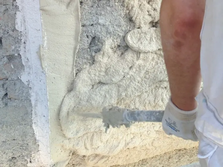 Detailaufnahme des Aufspritzens des Fixit 222 Aerogel Dämmputzes durch einen Verarbeiter mit orangenem T-Shirt
