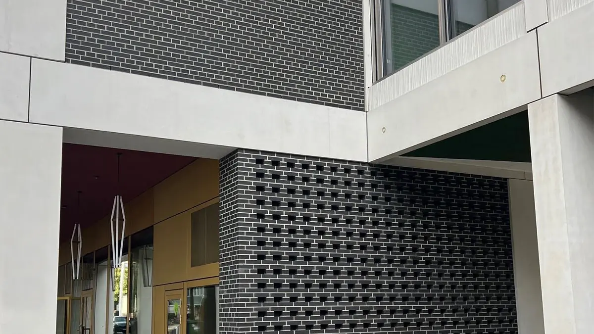 Ansicht der Aussenfassade mit den dunkelgrauen Mauerflächen mit Lochstruktur