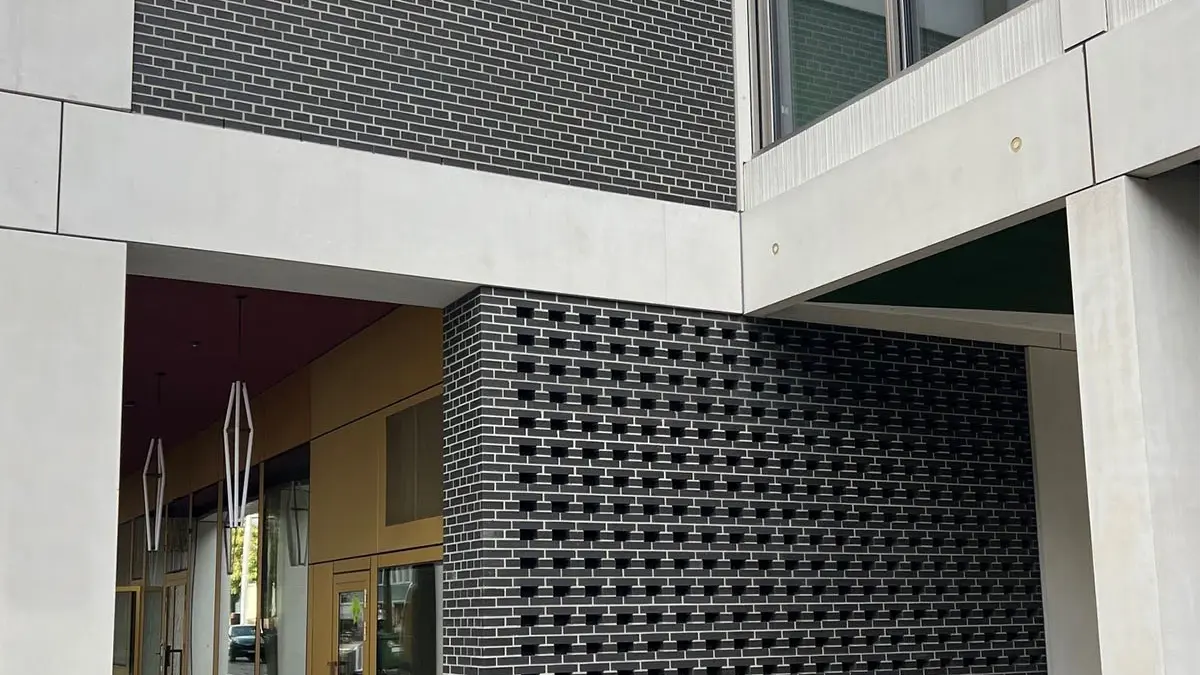 [Translate to French (CH):] Ansicht der Aussenfassade mit den dunkelgrauen Mauerflächen mit Lochstruktur
