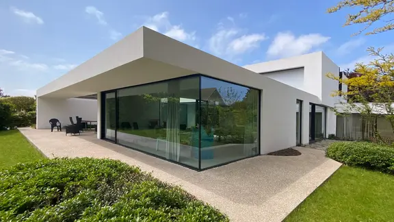 Modernes Einfamilienhaus mit grosser Glasfront und kubistischem Aussehen, weiss verputzt.