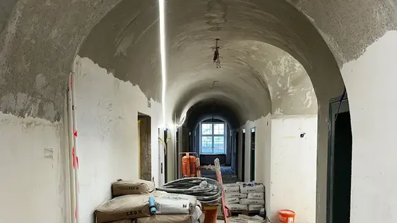 Couloir historique avec plafond voûté et une palette de produits d'assainissement Fixit